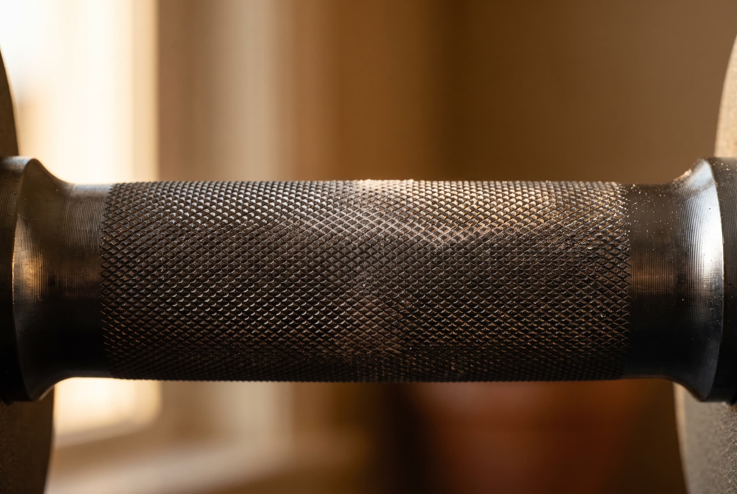 Chalk dust drifting through a warm light beam over dark knurled steel