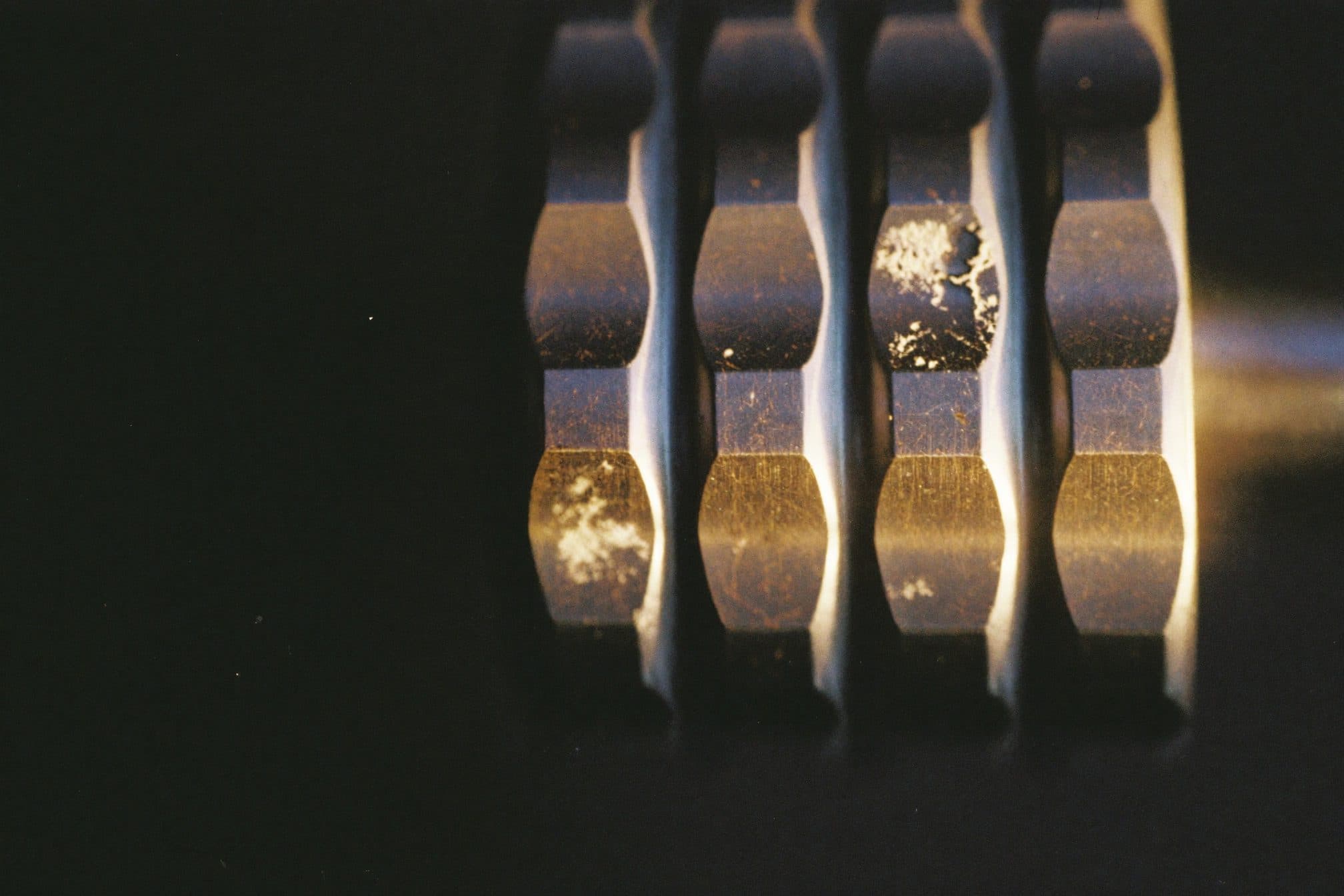 Dark dumbbell heads with chalk flecks in warm raking light