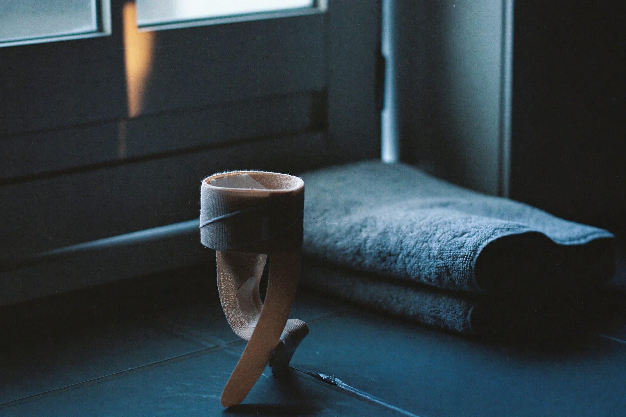 A rolled elastic support bandage beside a folded grey towel on cool tile