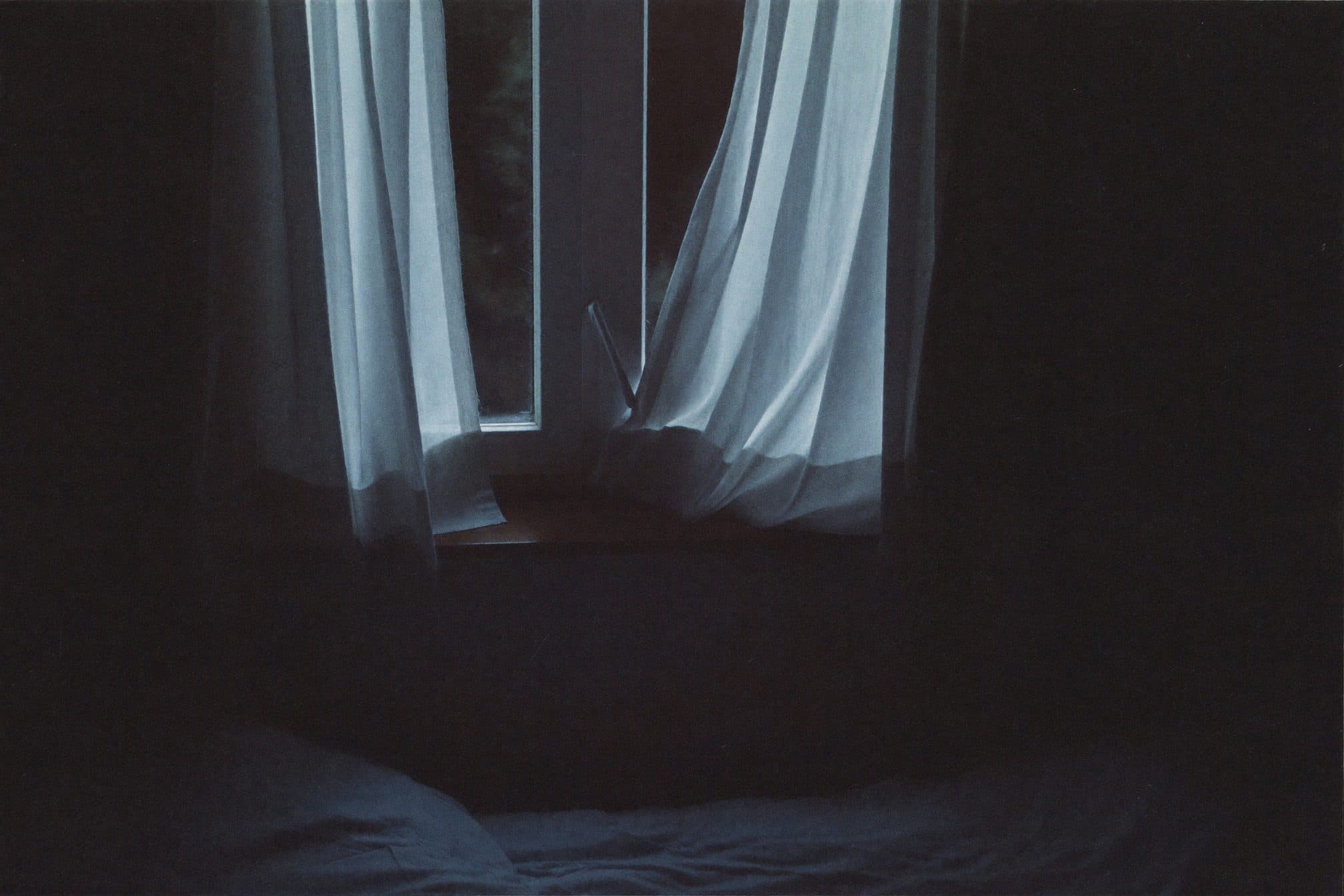 A dark bedroom window from inside, moonlight grazing linen curtains and a wooden sill