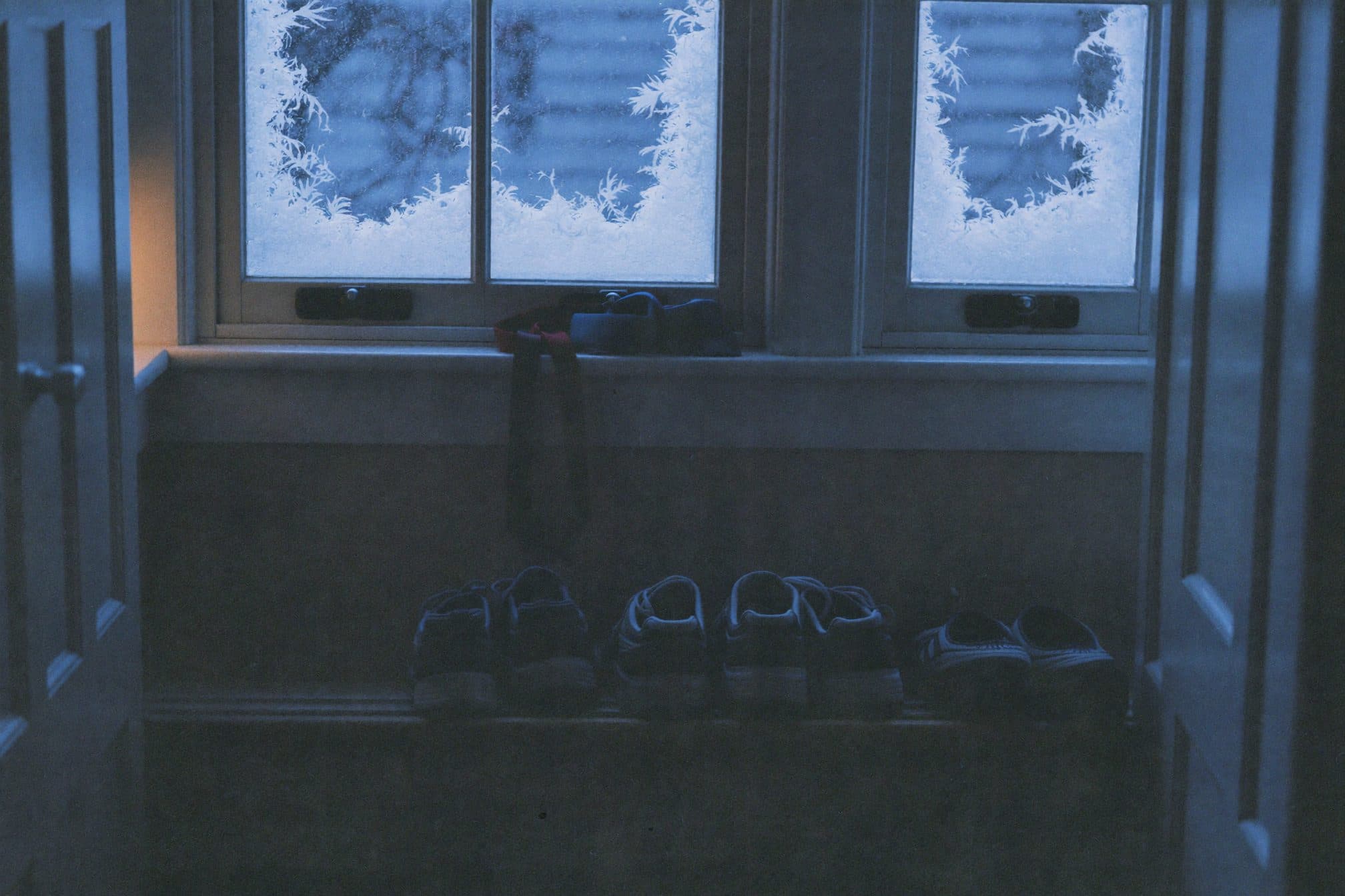 Running shoes below frosted windows in deep pre-dawn blue light